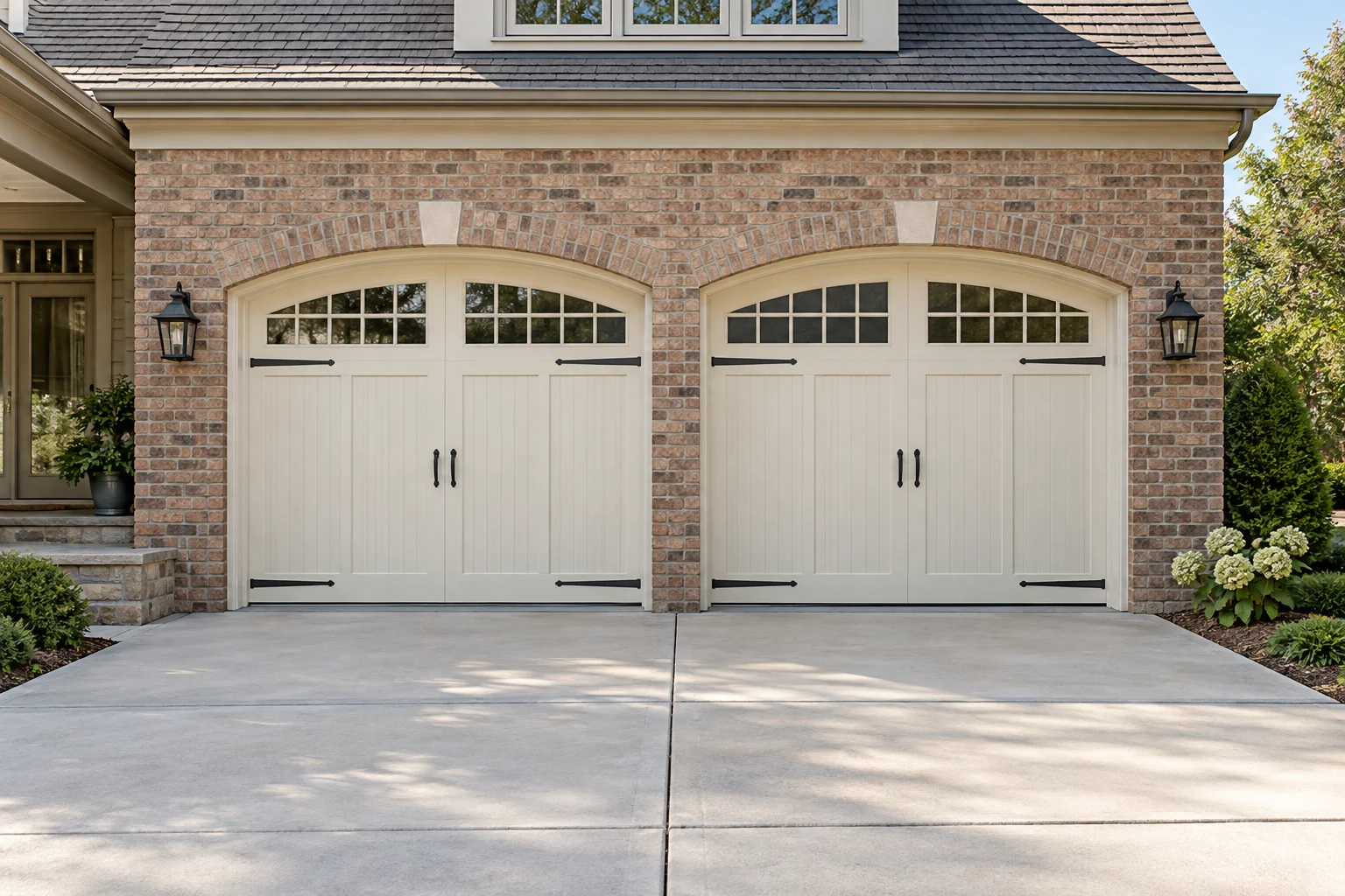 Cream carriage-house garage door with arched windows on a brick home