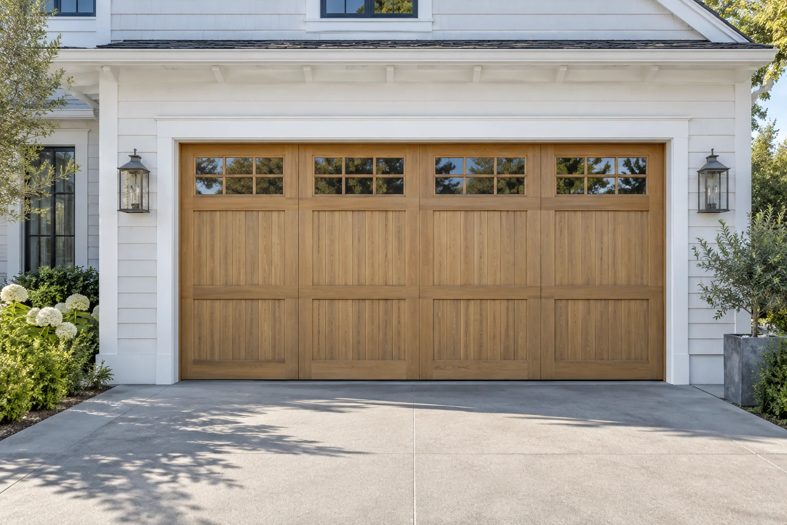 Natural oak garage door on a coastal home with white siding in daylight